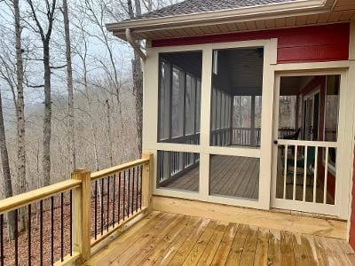 A screened in porch with a view of the woods.