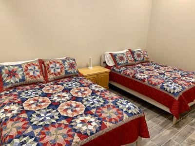 Two beds in a room with quilts on them.