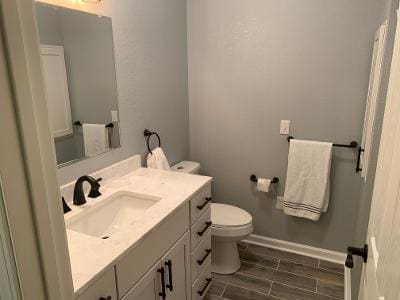 A bathroom with a sink, toilet and mirror.