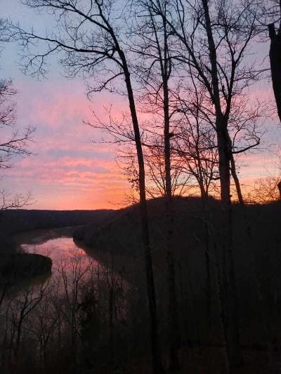 A sunset over a river with trees in the background.