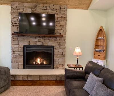 A living room with a stone fireplace and tv.