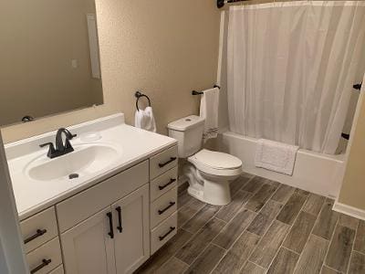 A bathroom with a toilet, sink and shower.