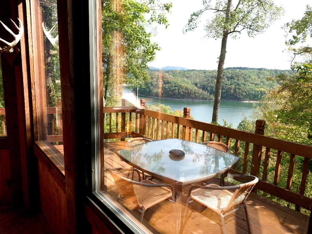 A deck with a table and chairs overlooking a lake.