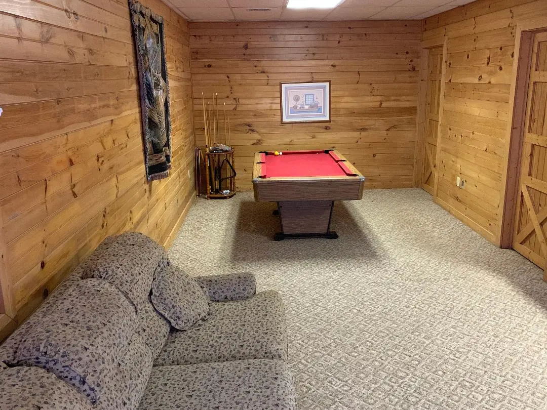 A living room with a pool table and a couch.