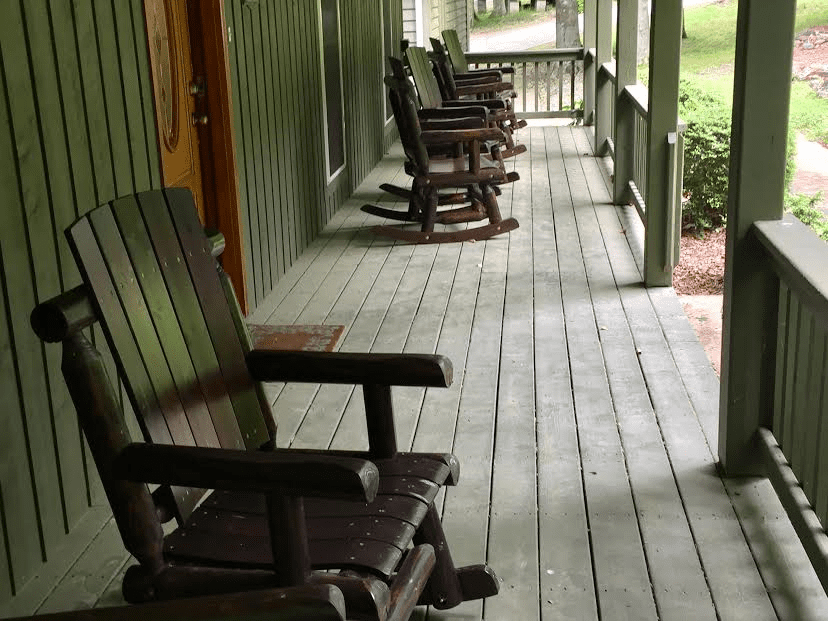 Four rocking chairs on the porch of a house.