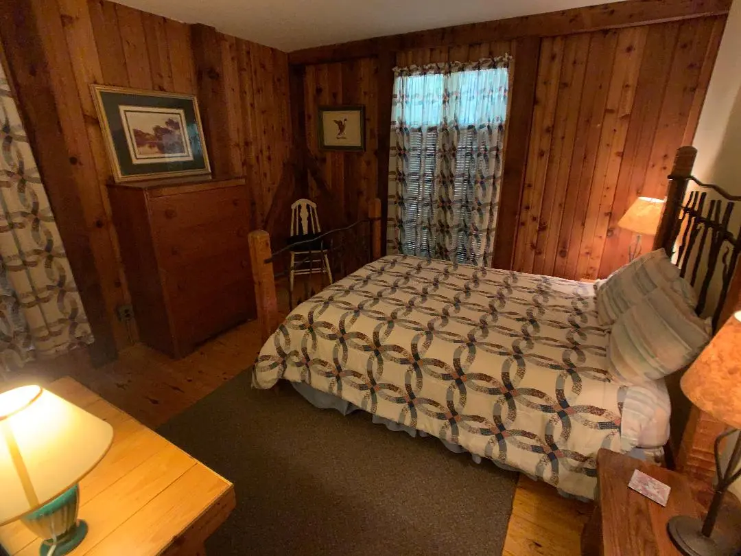 A bedroom with wood paneling and a bed.