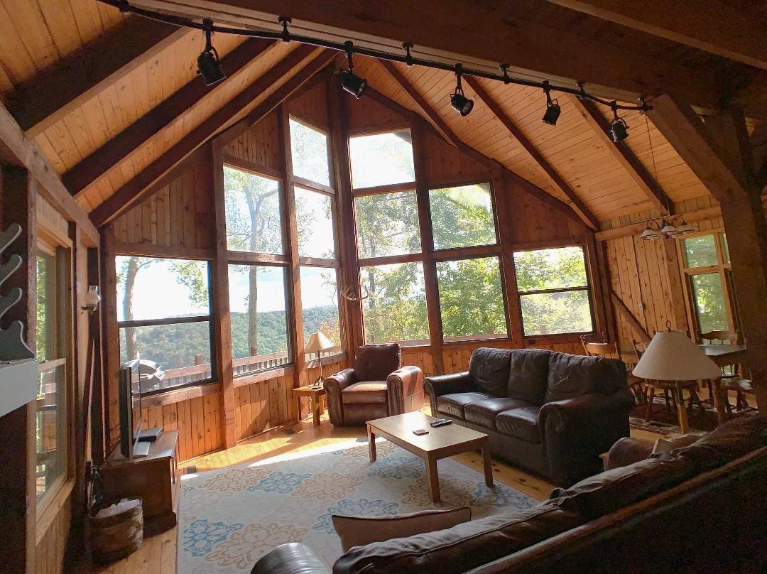 A living room in a log cabin with large windows.