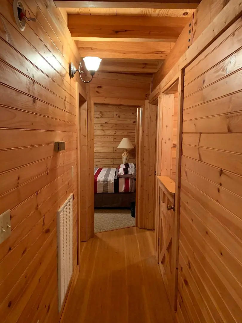 A hallway in a log cabin with a bed and a bedside table.