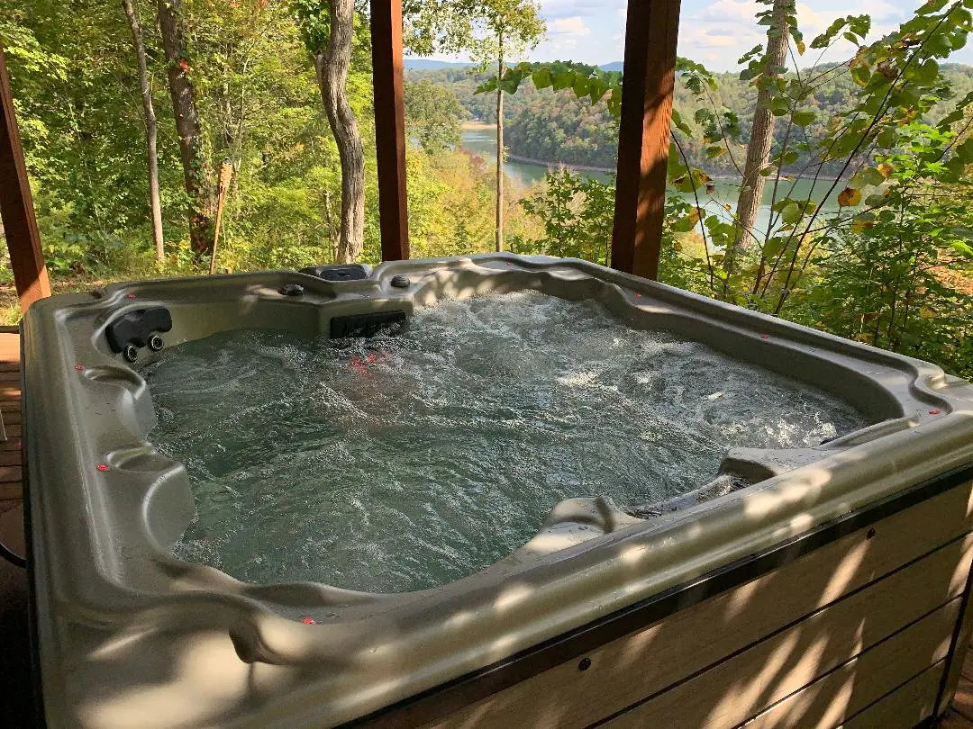 A hot tub on a deck overlooking a lake.