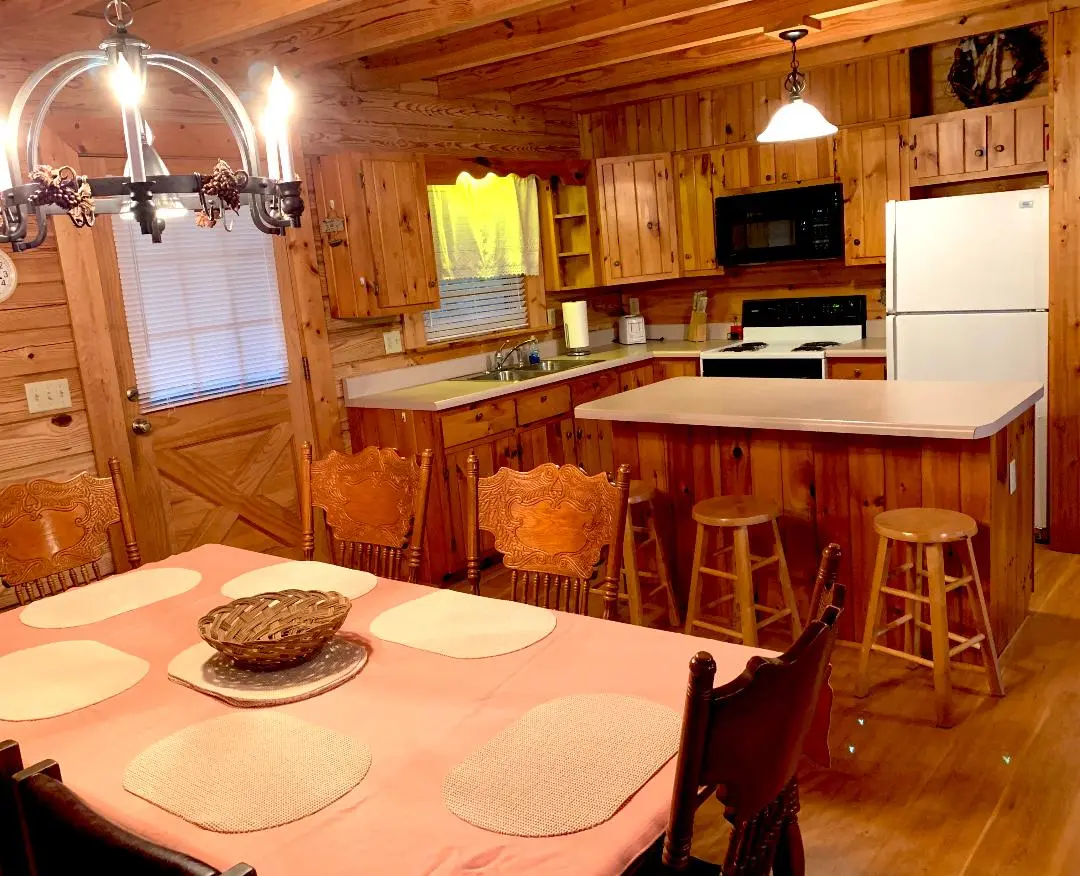 A kitchen in a log cabin with a table and chairs.