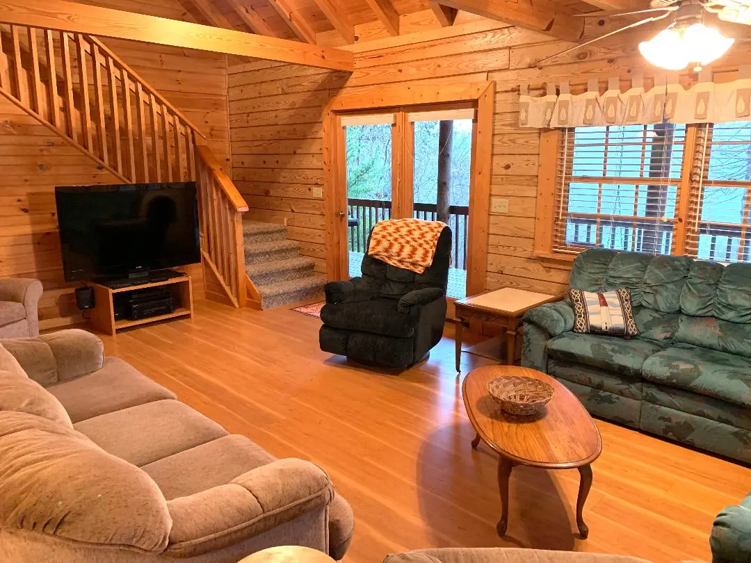 A living room in a log cabin with couches and a tv.