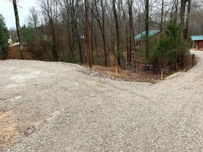 A gravel road leading to a wooded area.