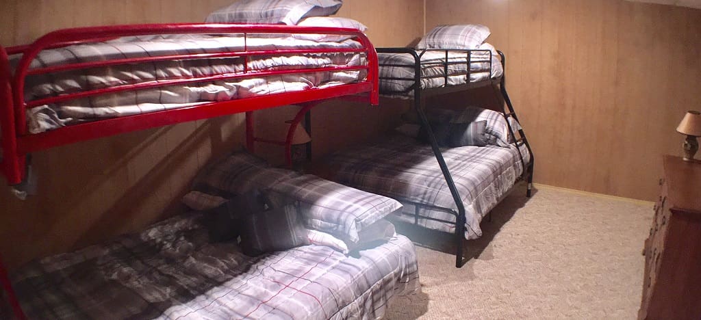 Three bunk beds in a room with wood flooring.