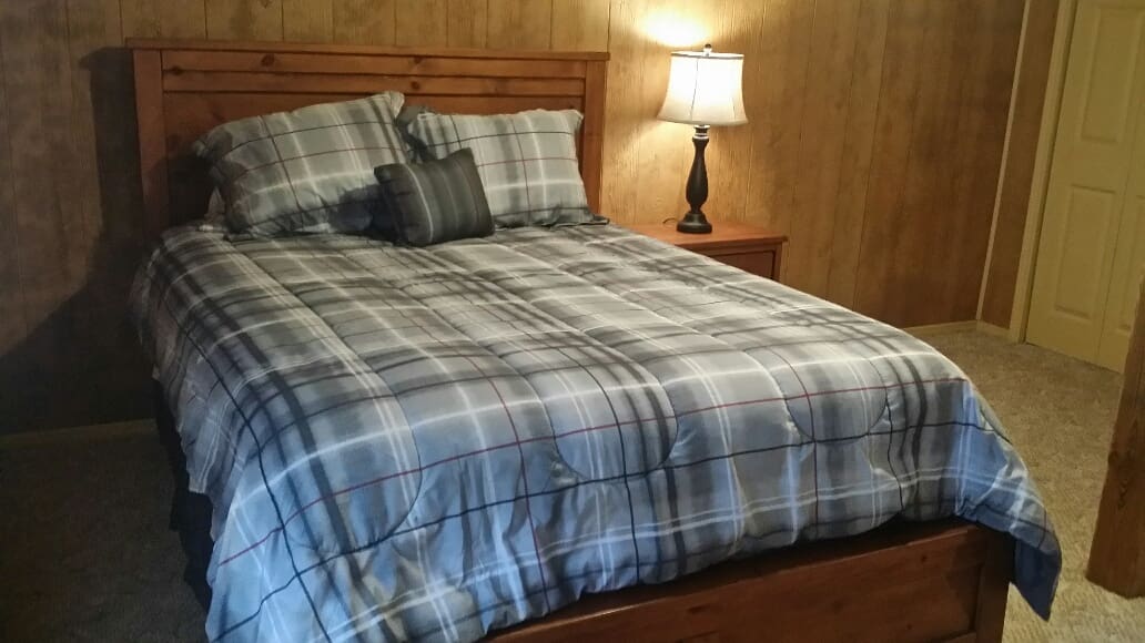 A bed in a bedroom with a plaid comforter.