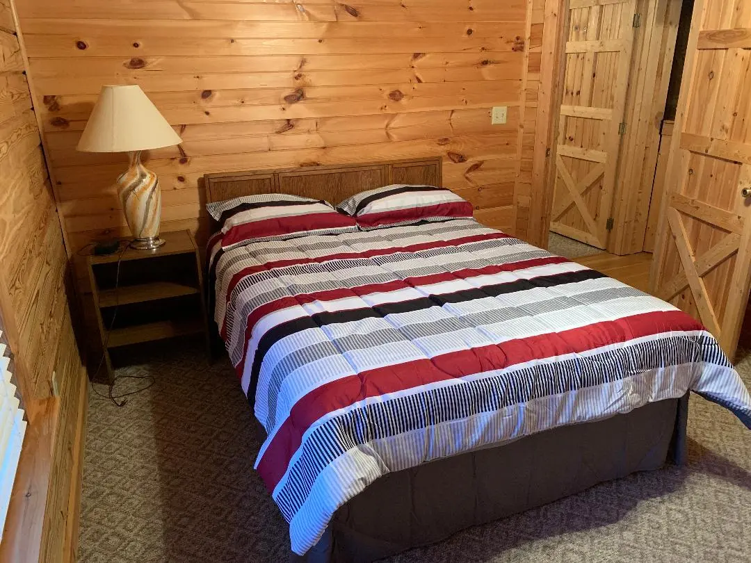 A bedroom in a log cabin with a bed and a nightstand.