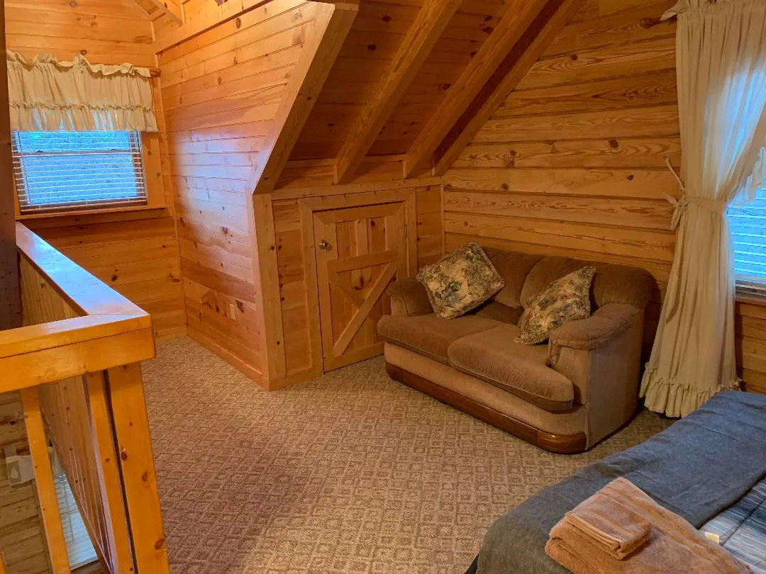 A bedroom in a log cabin with a couch and a bed.