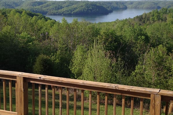 A view from a deck overlooking a lake and woods.