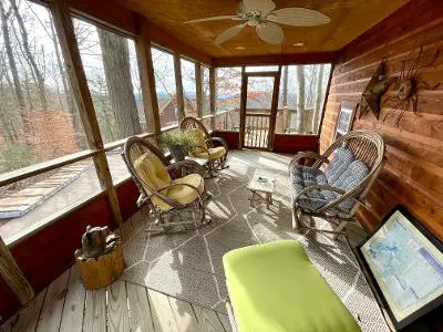 A screened in porch with rocking chairs and a view of the mountains.