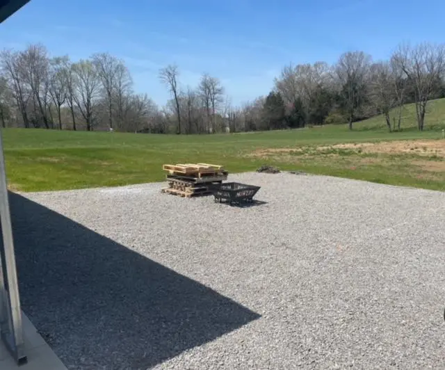 A gravel driveway with a fire pit in the middle.