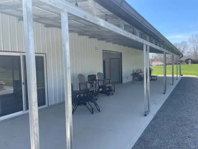 A covered patio with chairs and a grill.