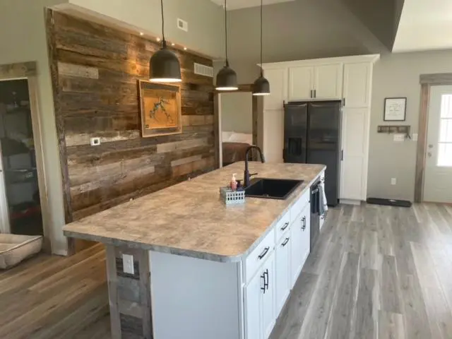 A kitchen with wood paneling and wood floors.