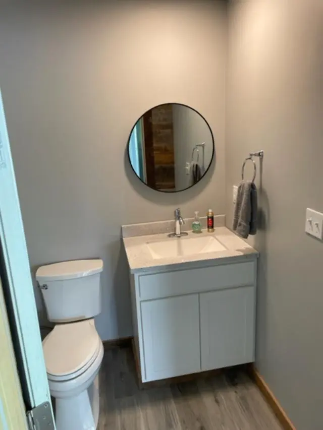 A bathroom with a toilet, sink and mirror.