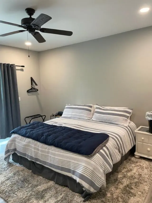 A bedroom with a bed and a ceiling fan.