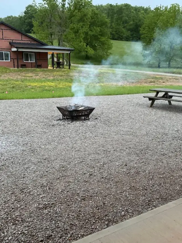 A fire pit in the middle of a gravel lot.