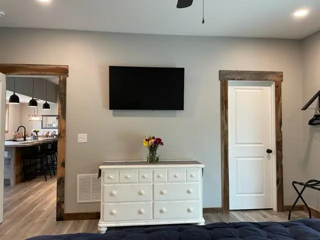 A bedroom with a bed, dresser and tv.