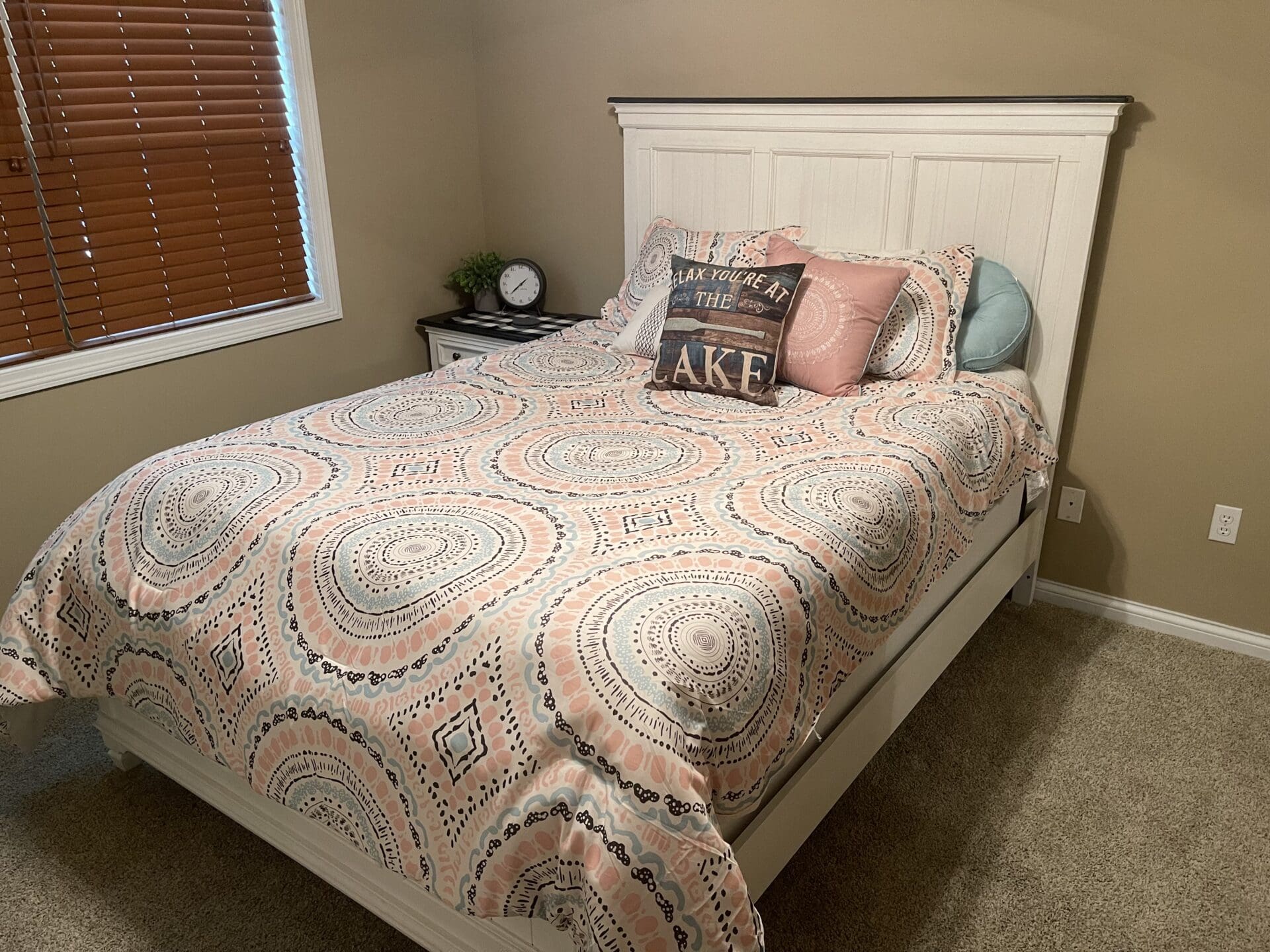 A bed in a bedroom with a pink and white comforter.