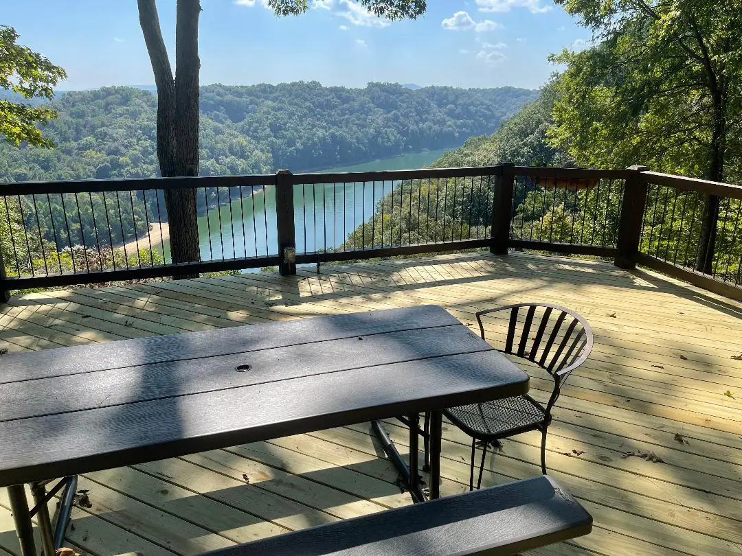 A deck overlooking a lake with a picnic table.