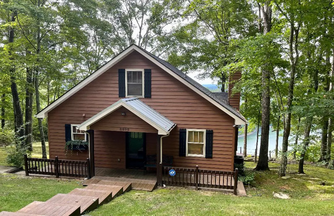 A small cabin in the woods next to a lake.