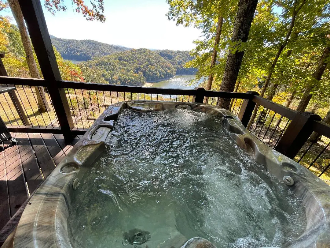 A hot tub on a deck overlooking a lake.