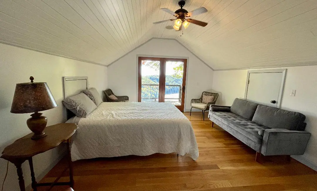 A bedroom with a bed, couch, and ceiling fan.