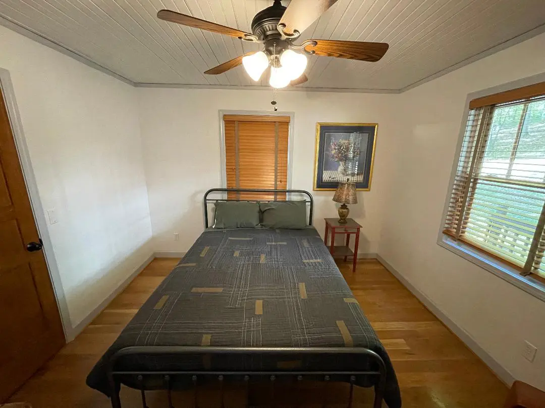 A small bedroom with a bed and a ceiling fan.