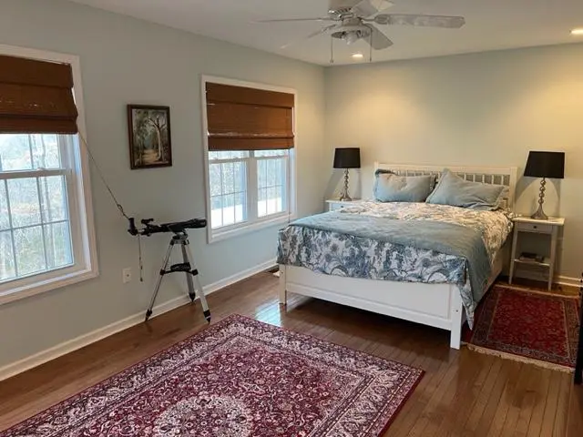 A bedroom with hardwood floors and a bed.