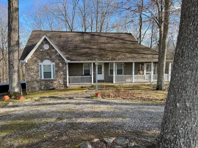 A stone home in the woods with a porch.