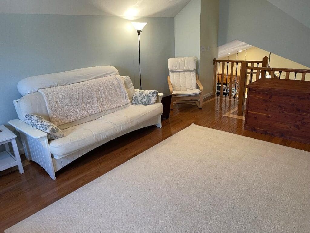 A living room with a white couch and stairs.