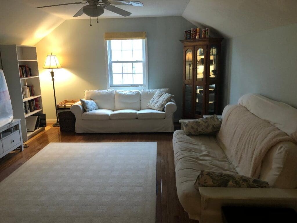 A living room with a white couch and a tv.