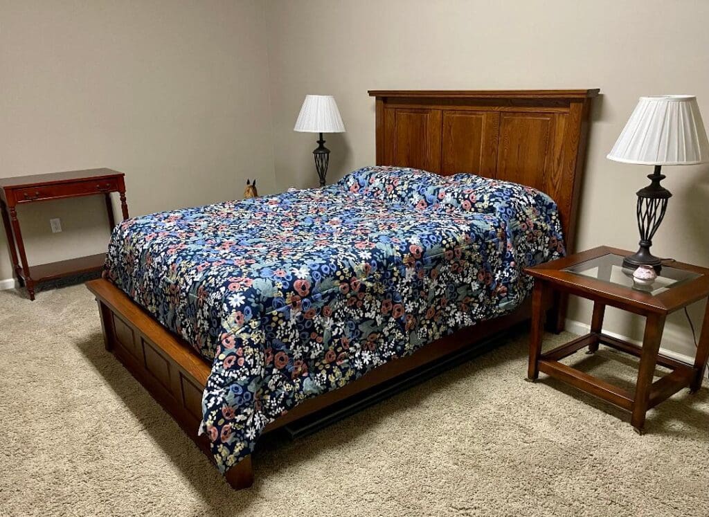 A bedroom with a bed and a nightstand.