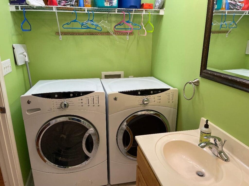 A laundry room with two washers and a sink.