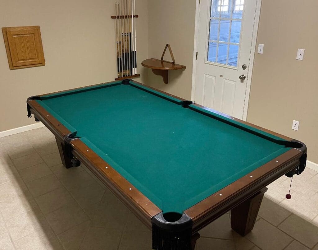 A pool table in a room with a pool cue.