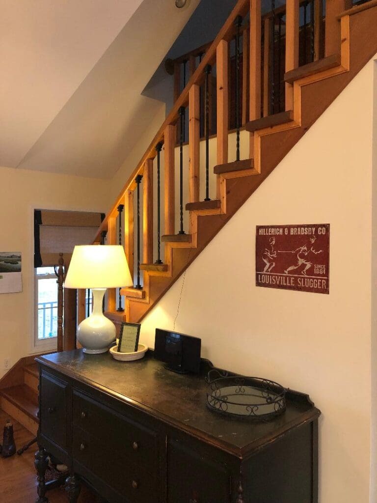 The stairs leading up to a room with a dresser and lamp.