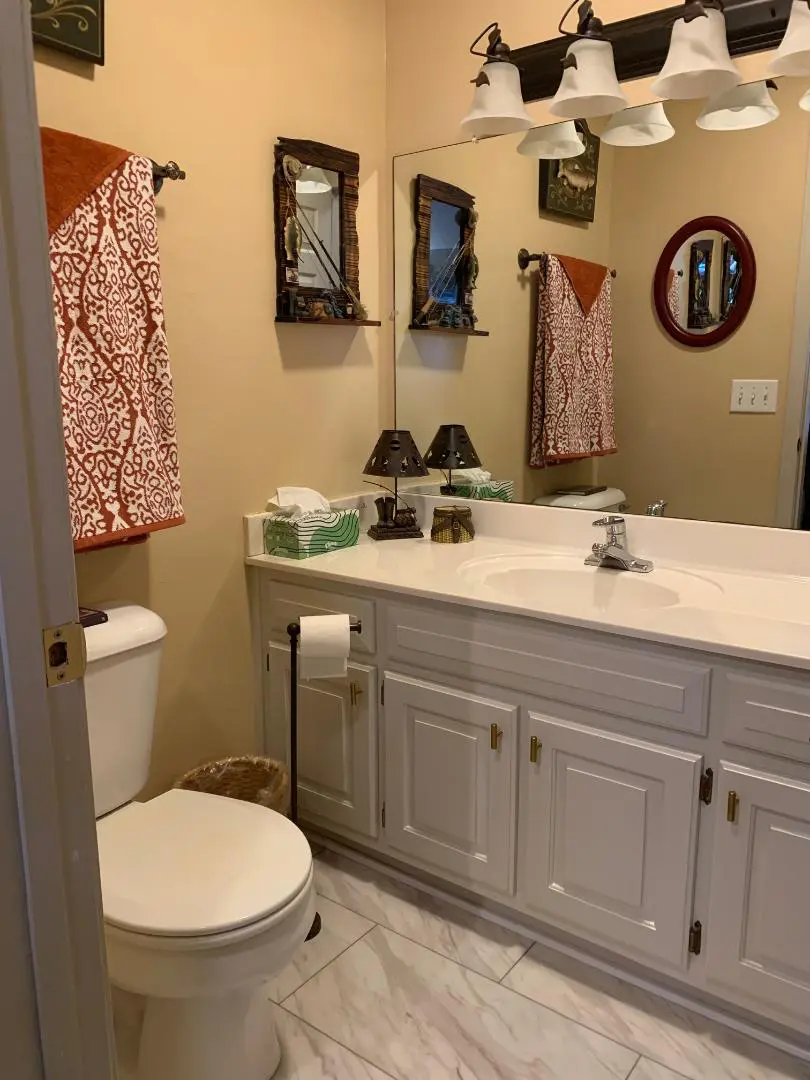 A bathroom with a toilet, sink and mirror.