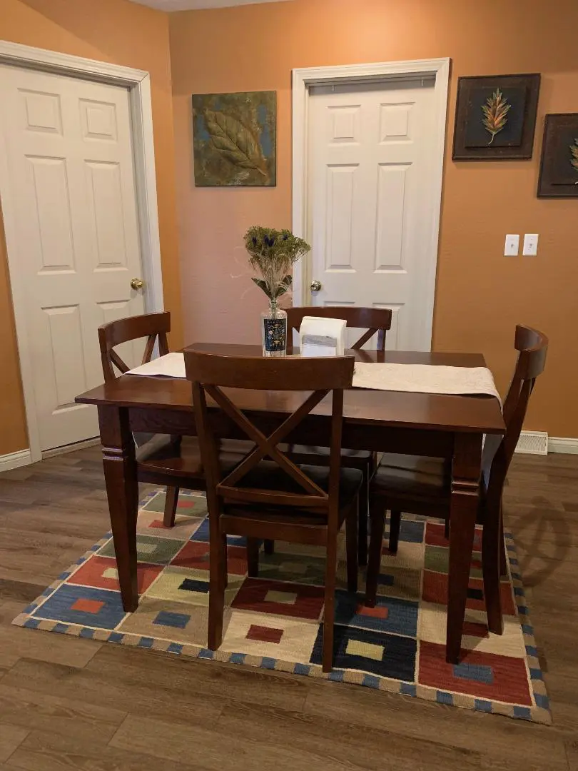 A dining room table with chairs and a rug.