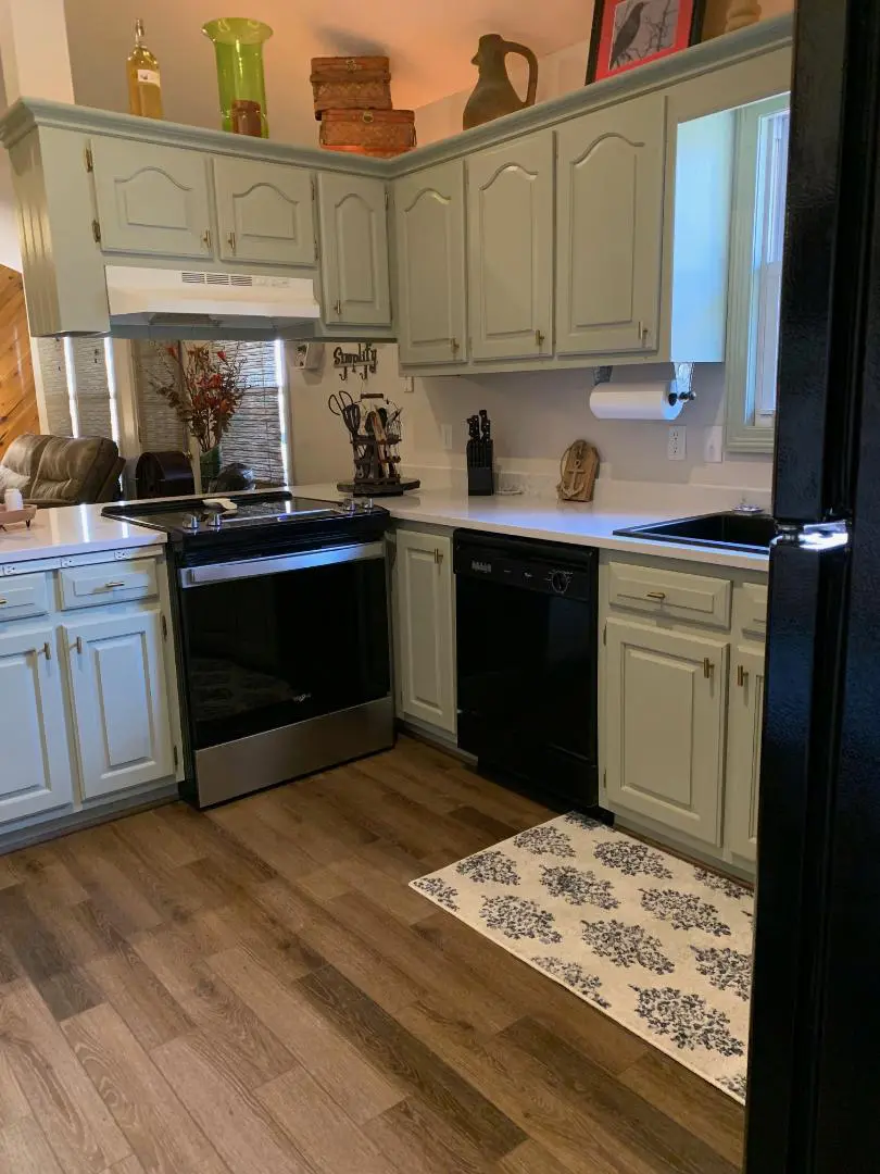 A kitchen with green cabinets and a wooden floor.