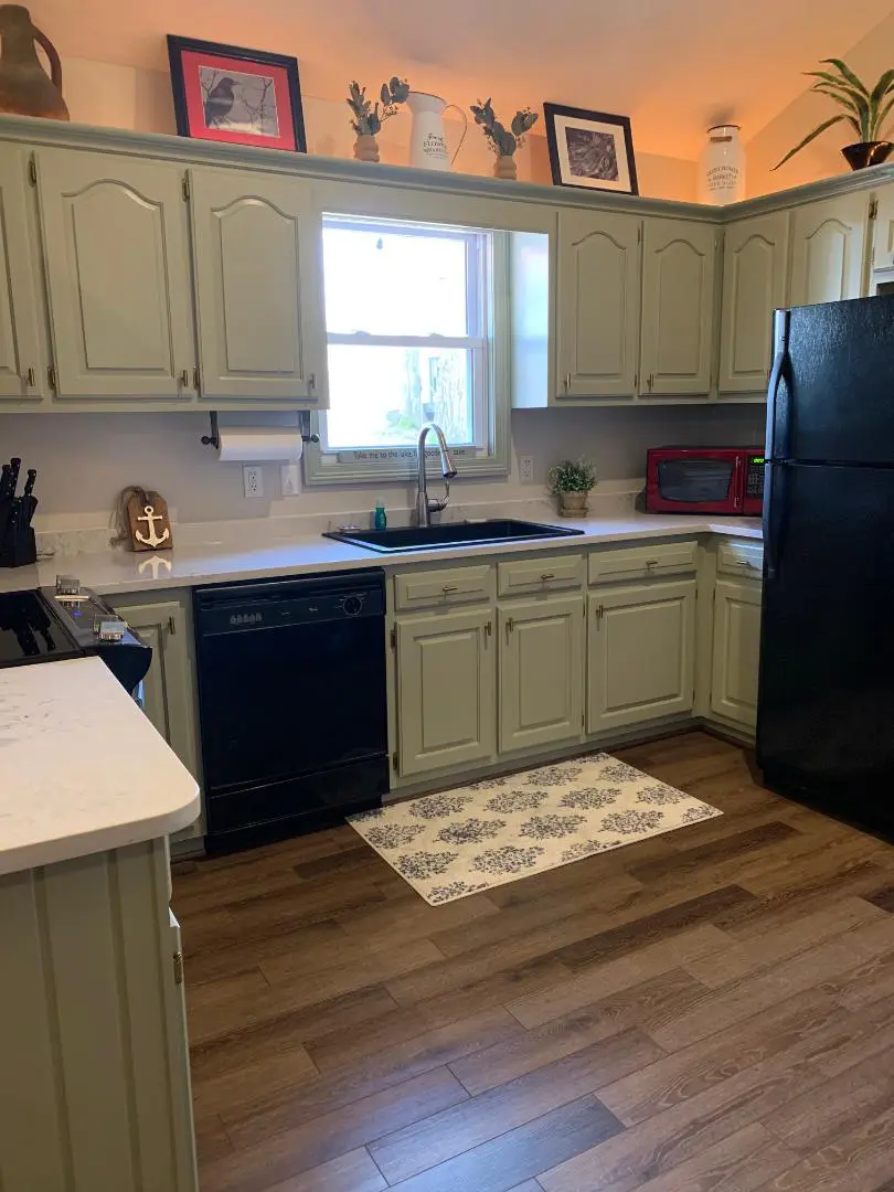 A kitchen with green cabinets and a black stove.