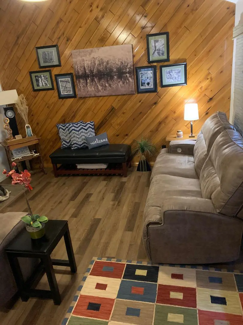 A living room with wood paneling and a couch.