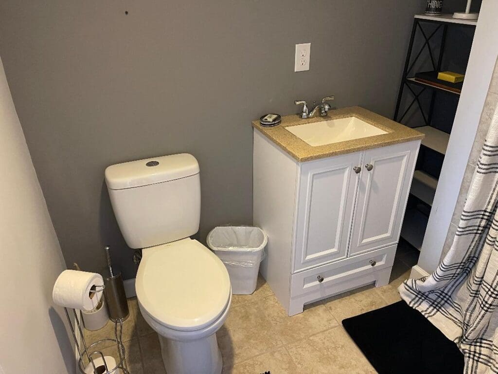 A small bathroom with a toilet, sink vanity, and various accessories.