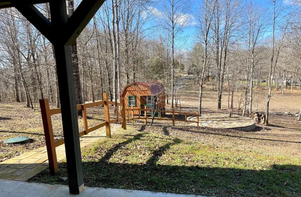 A wooden playground structure with a slide and swing set in a backyard on a sunny day.